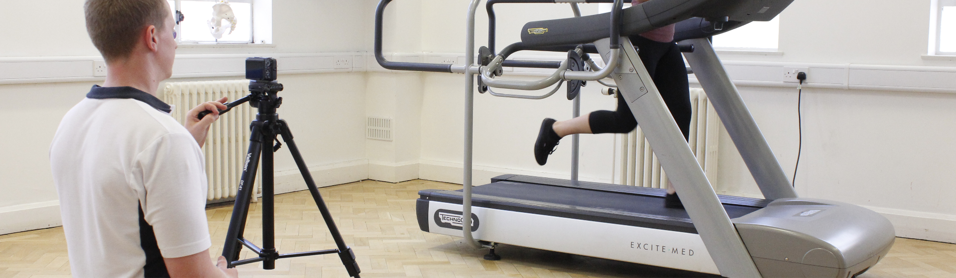 Physiotherapist recording running techniques of athlete on treadmill