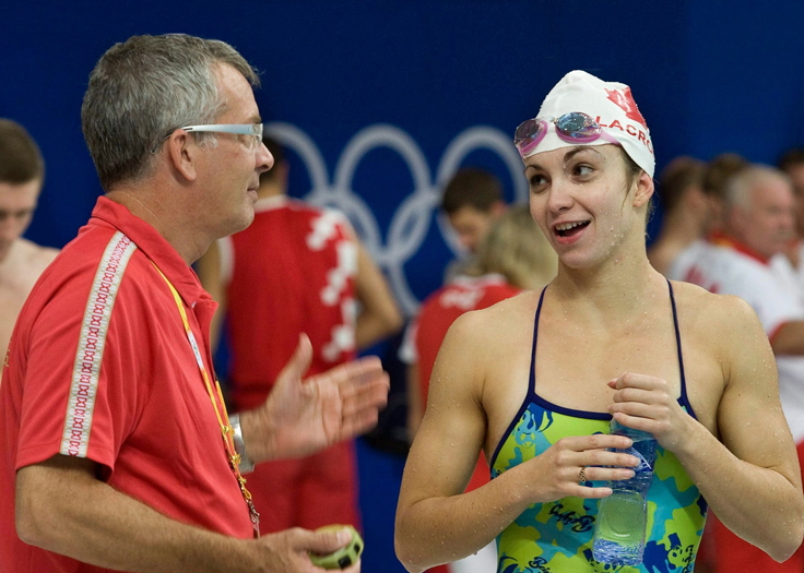 Swimming coach discussing performance with athlete swimmer after race