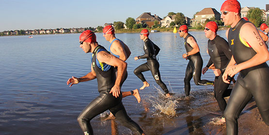 Group of athlete swimmers running into water to start race