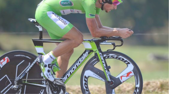 Athlete Cyclist cycling past a field