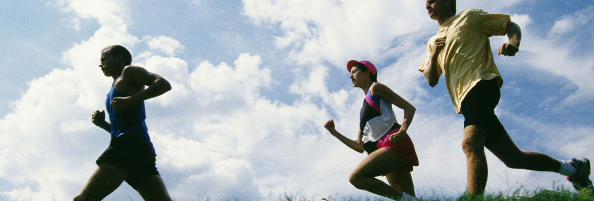 Group of triathletes running through field.