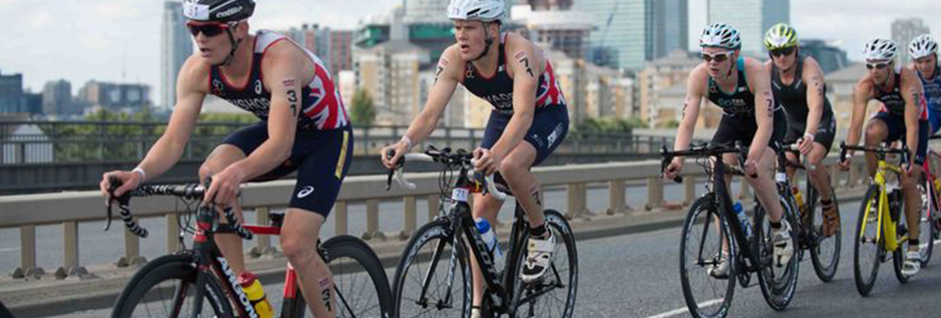 Group of athlete cyclists taking part in a race next to a city