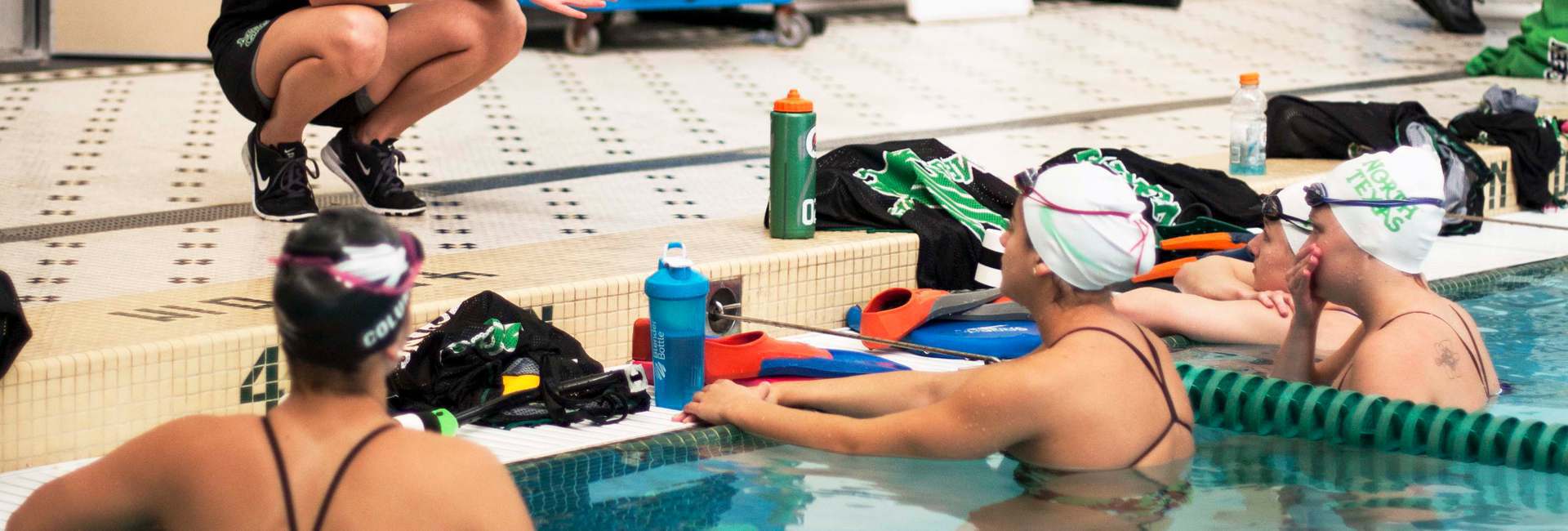 Swimming sports club talk with coach whilst training.