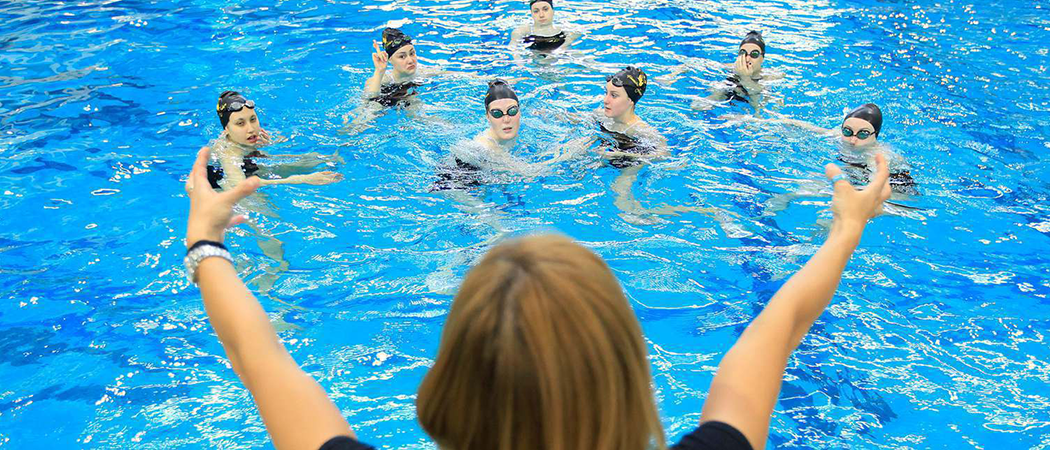 Group of Athlete Swimmers listening to coaches instructions in pool
