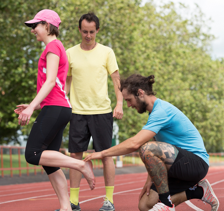 Athlete running coach supporting athlete runner on track