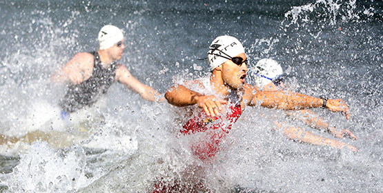 Group of athlete swimmers running into ocean to start race