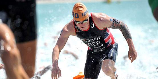 Group of athlete swimmers leaving water to finish race