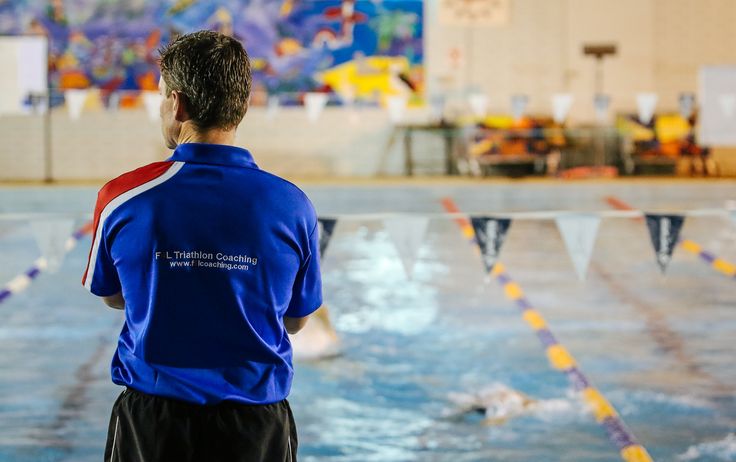 Swimming Coach observing athlete swimmers performance in pool