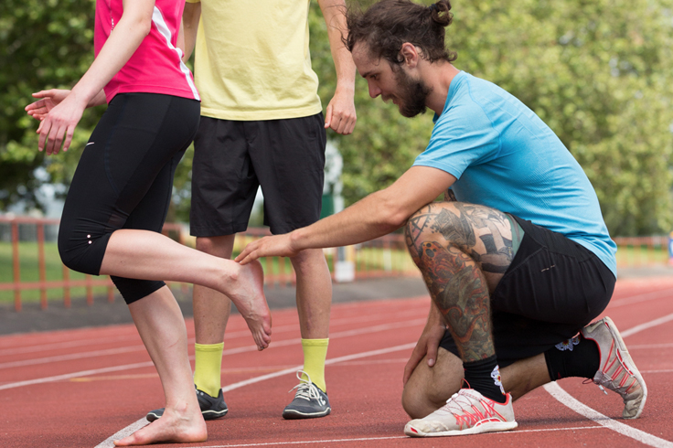 Running Coach supporting athlete runner on track