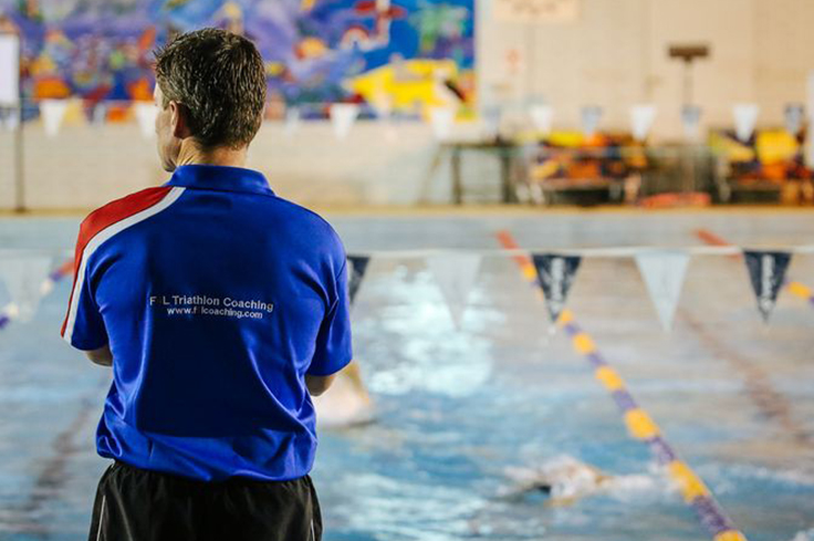 Swimming coach observing other swimmers in pool