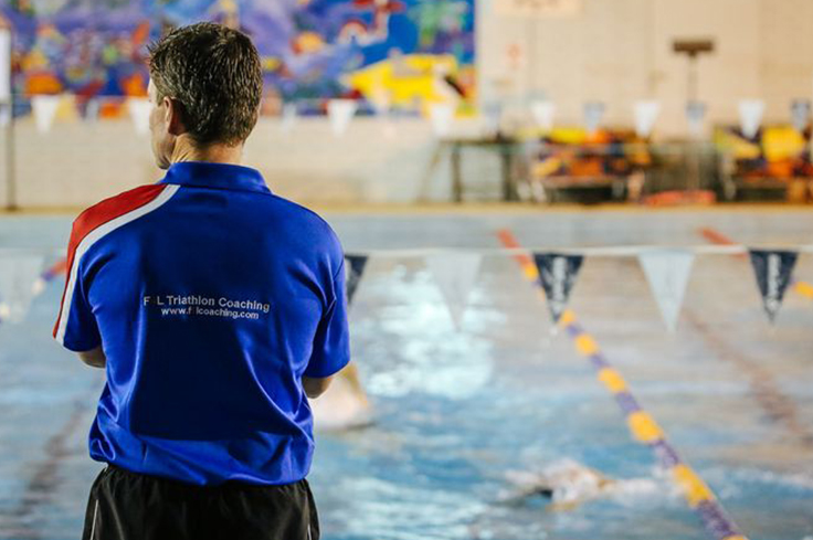 Swimming Coach observing athlete swimmers in pool