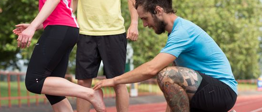 Teenagers friend helps tighten laces before run.